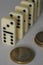 Standing domino bricks in curved pattern, Euro coins lying next to them