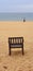 Standing on the edge in contemplation. One Empty wooden chair on beach