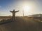 Standing man in the middle of the road opening arms for happy travel concept - alternative vacation with abandoned camping with