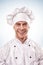 Standing smiling male cook in white uniform and hat