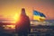 Standing Strong for Freedom: Man with Ukrainian Flag at Sunset Beach