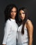 Standing together and standing tall. Portrait of two attractive young women wearing white blouses posing closely