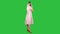 Standing young beautiful girl making a call on a green screen, chroma key.