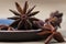 Star anise with and without seeds, in a clay dish on a light wooden surface. spice for cooking, medicine, cosmetics. background