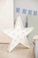 Star lamp on the floor against the background of a gray wall with holiday flags. Big star with bulbs. Modern home decoration. Deco