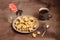 Star-shaped cookies lie on a beige plate, tea in a grey cup with a heart and a geranium flower on a brown wooden background.