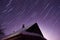 Star trails over the house late at night, purple night sky,
