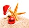 Starfish, christmas buable and Santa Claus hat on the sand