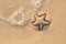 Starfish drawn on the beach sand being washed away by a wave. Foaming sea wave coming to wash a picture on wet yellow