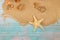 Starfish with seashells on sea sand on blue wooden background. Papyrus from the glass bottle with cork