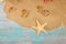 Starfish with seashells on sea sand on wooden background. Papyrus from the glass bottle with cork