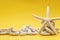 Starfish, stones and rope on a plain yellow background