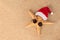 Starfish in sunglasses and a santa claus hat on the golden sand. Christmas concept at sea. Copy space.