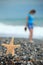 Starfish and young girl on stone seacoast