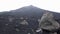 Stark and desolate volcano creater landscape with black lava sand and rocks and other craters behind