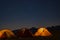 starry night as seen from mountain campsite in himalaya. tents illuminated from inside lights.