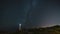 Starry night milky way timelapse in a coastal landscape and a lighthouse on the background