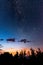 starry night sky with Milky Way above the forest trees