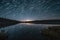 starry sky above tranquil lake, with star trails visible