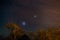 The starry sky and the majestic Magellanic Clouds, outstandingly bright, captured in Africa. Acacia trees and straw hut in the for