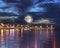 Starry sky and moon  , city night neon light reflection on sea water at pier promenade