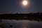 the stars in the night sky are reflected in the mirror smooth surface of the lake, and the moon illuminates