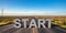 Start, beginning concept. Text sign on a long straight road, blue sky background. 3d illustration