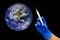 Start of covid-19 vaccination. Female hand in blue medical glove with syringe giving vaccine injection to planet Earth