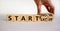 Start now or later symbol. Businessman turns wooden cubes and changes words `start later` to `start now`. Beautiful white
