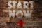 Start now word with red arrow on wooden