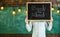 Start of school year concept. Teacher holds chalkboard in front of face. Man welcomes students, chalkboard on background