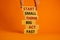 Start small think big symbol. Words `Start small think big act fast` on wooden blocks on a beautiful orange background.