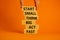 Start small think big symbol. Words `Start small think big act fast` on wooden blocks on a beautiful orange background.