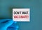 Start vaccination symbol. Hand in blue glove with white card. Concept words `Do not wait. Vaccinate`. Medical and COVID-19