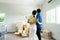 Start your new family in new house. Asian couple hugging together and looking at room in new house with many stuff on the floor