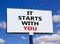 It starts with you symbol. Words `it starts with you` on white billboard. Beautiful blue sky. Business, it starts with you conce