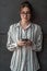 Startup businesswoman in shirt with a glasses using smartphone while standing in front of gray wall during break from