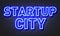 Startup city neon sign on brick wall background.