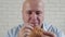 Starved Person Eating a Tasty Hamburger, Linking His Fingers Enjoy a Delicious Snack in a Fast Food Restaurant