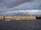 The State Hermitage Museum in St. Petersburg, with the touristic boats in front of it, on the background of dramatic stormy sky.