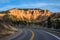 State Road 14 leads toward cliff of orange and red rock towers and hoodoos