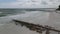 Static aerial shot of a cloudy blue sky over some tropical Florida beach waves a jetty and dock