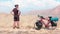 Static back view caucasian male cyclist standing by red touring bicycle looking to scenic mountains background.