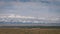 Static background on close-up powerful mountains. Dry steppe, mighty snow-capped mountains, cumulus low clouds.Beautiful