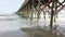 Static Medium Shot of the end of the Wooden Pier out in the ocean. People walking along the pier. Beautiful aerial perspective of