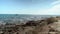 Static shot of a beach in side city, Turkey with boat sailing and waves crashing towards rocky coast