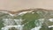 Static top down view of tropical beach, foamy ocean waves washing sand.