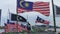 Static view of Malaysian and Terengganu state flags fluttering on a windy day against traditional wooden fishing boat docking at a