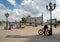 Station square with fountains, people, a marble pillar near the main railway station of the city on a sunny summer day