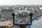 Stationary binoculars for tourists on the observation deck. The binoculars are aimed at the blurry modern city. Services for